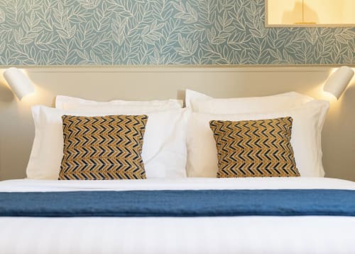 Luxury bed at Clos des Moulins in Poitiers with patterned cushions, white linens, and geometric headboard wallpaper