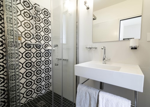 Modern bathroom in Clos des Moulins B&B, Poitiers, featuring black patterned tiles, walk-in shower, white sink, and
