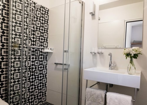Modern bathroom in Clos des Moulins with geometric black and white tile shower, floating white sink, and chrome fixtures in