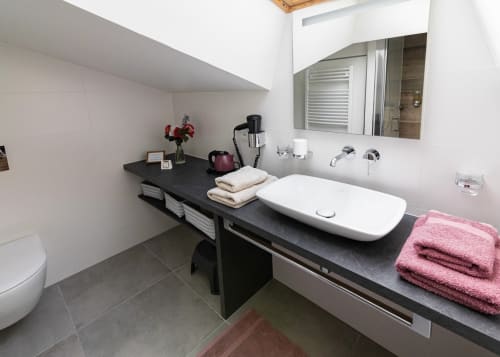 Salle de bain moderne du Clos des Moulins avec vasque noire, lavabo blanc, miroir, serviettes et accessoires de toilette à Poitiers