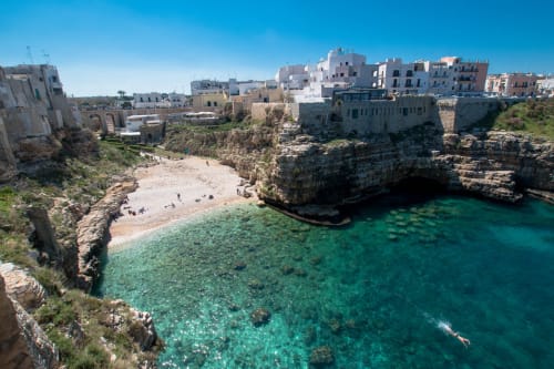 Petite crique turquoise avec plage de sable, falaises rocheuses et maisons blanchies à la chaux à Santeramo in Colle, Italie