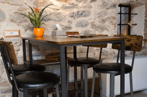 CasaRosada dining area in Vidracco with rustic stone wall, wood table, and black chairs