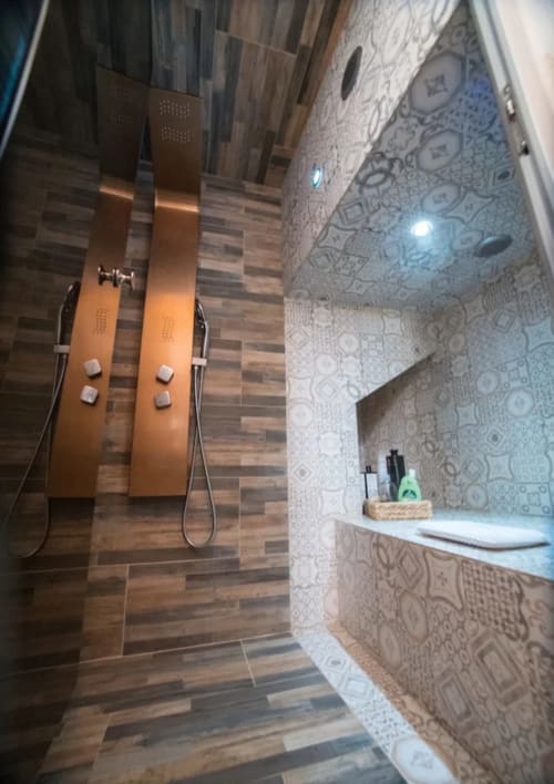 Modern bathroom at CasaRosada B&B in Vidracco with dual copper showerheads, wood-look tiles, and patterned walls