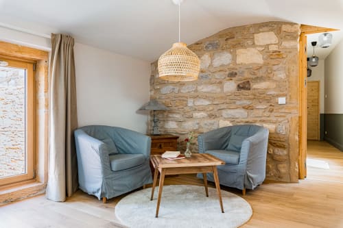 Coin salon avec fauteuils, table basse et tapis rond beige, mur en pierres apparentes, chambre air, maison de pagneux, chambres d'hôtes en Beaujolais des Pierres dorées 