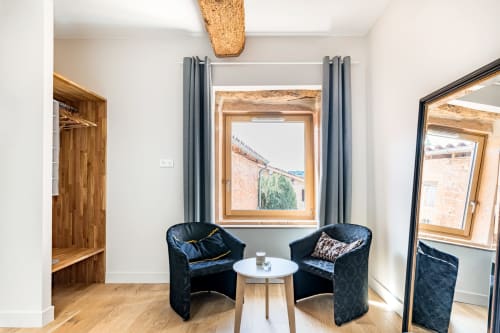 Coin détente devant la fenêtre avec deux fauteuils et une table basse dans la chambre bois, maison de pagneux, chambres d'hôtes en Beaujolais des Pierres dorées 