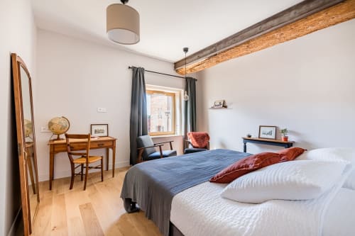 vue d'ensemble avec lit double, fenêtre et rideaux, fauteuils, bureau, poutre apparente en bois et IPN, chambre métal, maison de pagneux, chambres d'hôtes en Beaujolais des Pierres dorées 