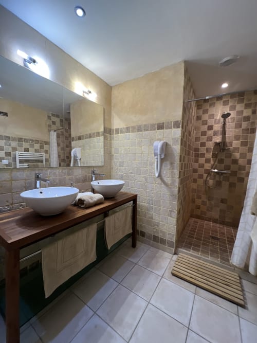 Salle de bains moderne du Lapin sur le Toit avec vasques doubles, douche à l'italienne et revêtement carrelage chaleureux à Rouffignac, France
