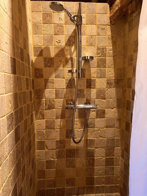 Douche moderne avec mitigeur chromé et pomme de douche cascade dans la salle de bain de la Rouffignac au Lapin sur le Toit, équipée de