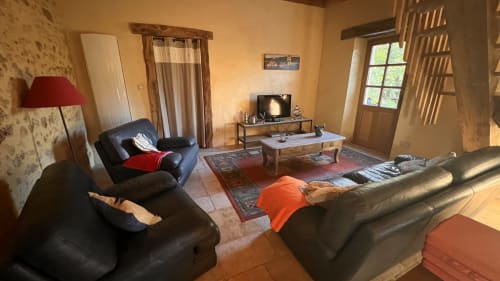 Vaste salon du Lapin sur le Toit à Rouffignac avec sièges en cuir noir, télévision et décoration traditionnelle