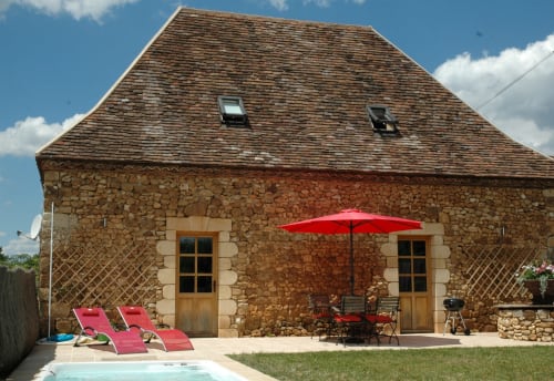 Cottage en pierre Le Lapin sur le Toit avec parasol rouge, transats et piscine à Rouffignac, France
