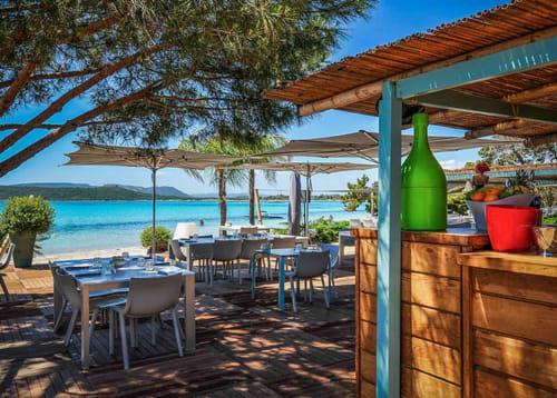 Alma Rossa beachfront restaurant terrace in Lecci with turquoise sea views, shaded dining tables, and Mediterranean coastal