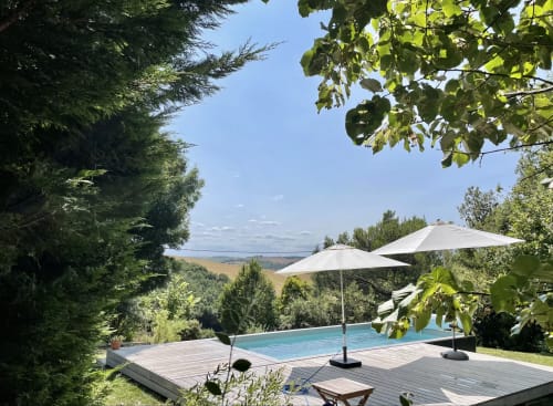 Luxury pool terrace at Maison Monsieur Léger in Montaut with umbrellas, countryside views, and surrounding greenery