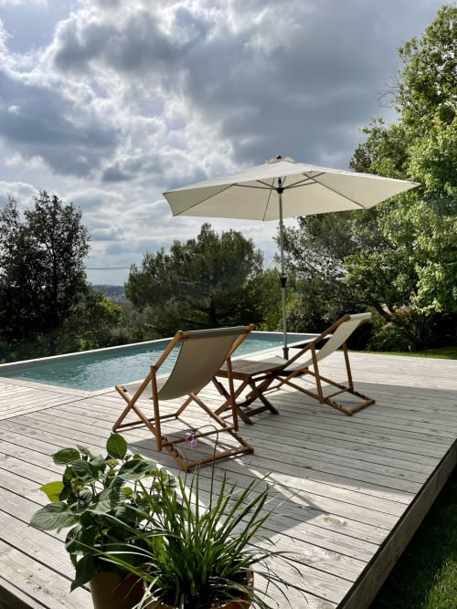 Poolside deck at Maison Monsieur Léger with loungers, umbrella, and countryside views in Montaut