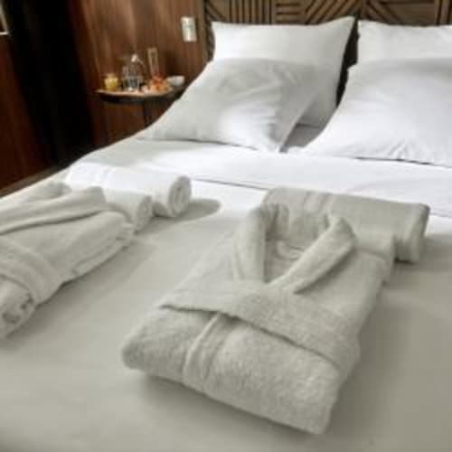 Lit de luxe aux draps blancs et serviettes roulées à Le Gîte du Miroir à Domérat