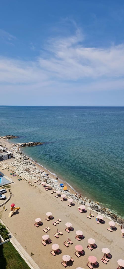 Vista sulla spiaggia di Lamar Suites Misano Adriatico con sabbia dorata, ombrelloni colorati, lettini e il Mar Adriatico turchese