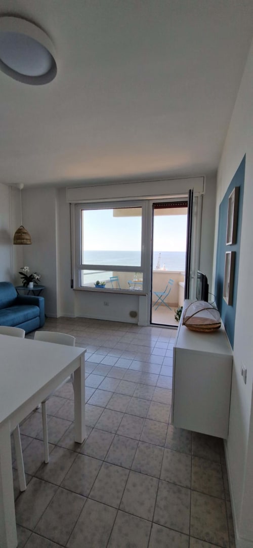 Seafront suite living room with sea view balcony, dining table, blue sofa, and modern furnishings at Lamar Suites