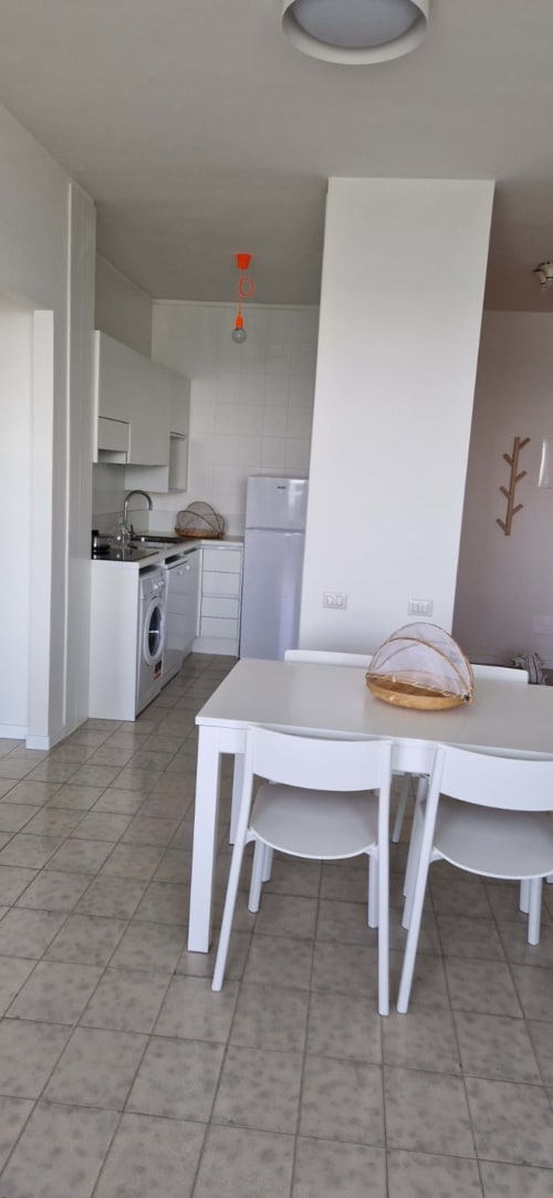 Modern kitchen-dining area in Lamar Suites Seafront Apartments, Misano Adriatico with white cabinetry and dining table