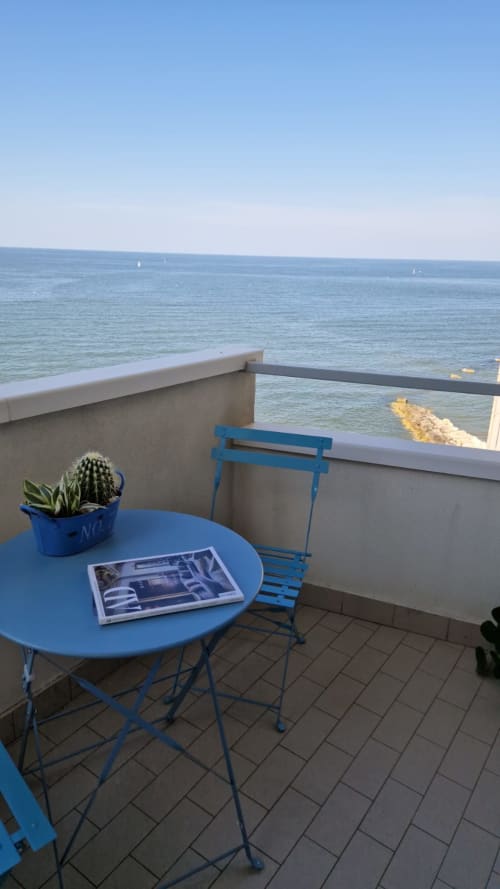 Seafront balcony at Lamar Suites with blue table, chair, cactus plant, and sea view overlooking Misano Adriatico.