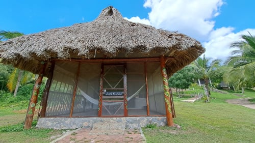 Bungaló con techo de palma en el hostal Cayuco Maya en Bacalar, con porche cerrado y vistas al lago