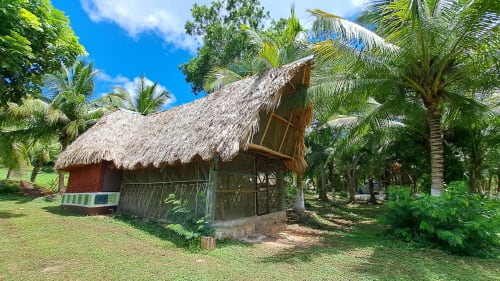 Bungalow con techo de paja en el albergue Cayuco Maya en Bacalar, rodeado de palmeras y vistas al lago