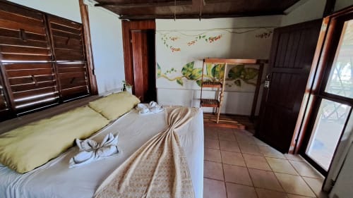 Espaciosa habitación de hostal en Cayuco Maya, Bacalar, con muebles de madera, vistas al lago y paredes decoradas