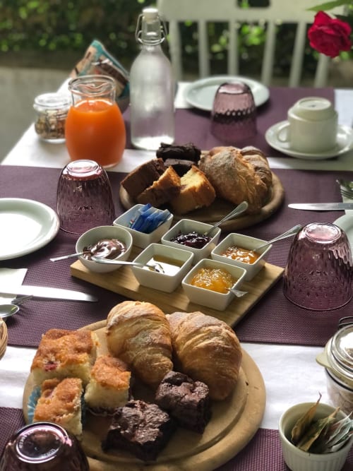 Colazione all'Agriturismo Il Pomo d'oro con cornetti freschi, pani, marmellate, succo d'arancia e pasticcini su tavolo viola