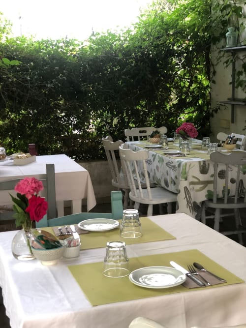 Allestimento per cena all'aperto presso l'Agriturismo Il Pomo d'oro con tavoli bianchi, tovagliette lime e rigoglioso sfondo verde