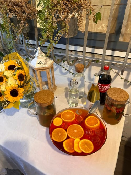 Tavolo per bevande all'aperto presso l'Agriturismo Il Pomo d'oro con grande punchbowl rosso, girasoli, piante sospese e rinfreschi