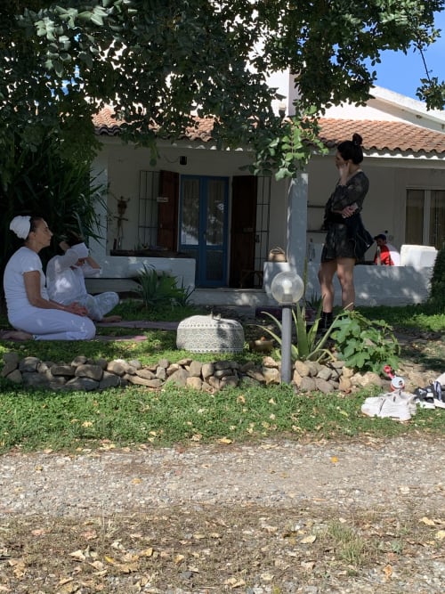 Ospiti che si rilassano nel giardino cortilizio dell'Agriturismo Il Pomo d'oro, Assemini con edifici bianchi e vegetazione lussureggiante