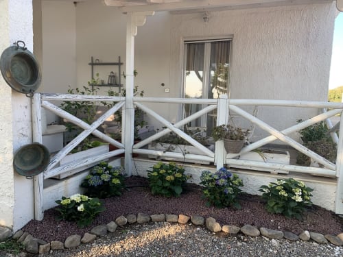 Suggestiva area esterna all'Agriturismo Il Pomo d'oro con ringhiere in legno bianco, piante fiorite e dettagli in pietra ad Assemini