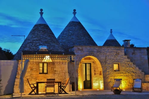 Trulli Vulés B&B a Ostuni illuminato al tramonto, con tradizionali costruzioni in pietra a forma di cono e luci calde