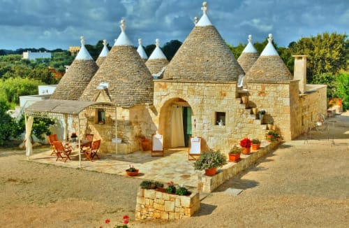 Bed and breakfast Trulli Vulés a Ostuni con caratteristici tetti in pietra a forma di cono, vasi in terracotta e patio rustico.