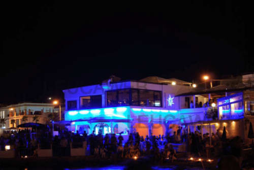 Hotel Panoramici Monolocali a Leuca di notte con illuminazione LED blu vibrante e ospiti che godono il luogo esterno