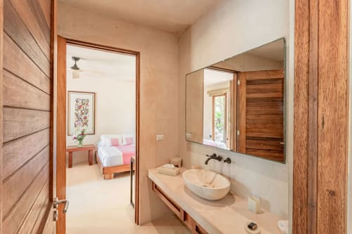 Modern bathroom with dual vessel sinks and wooden accents at Cantarena House villa in Tulum, overlooking bedroom beyond