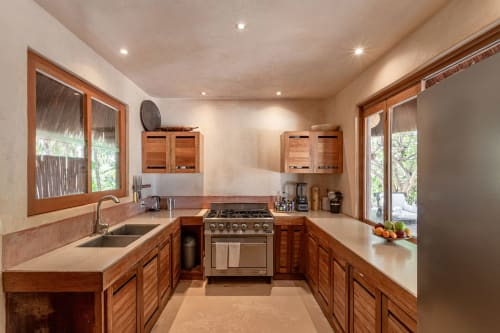 Spacious kitchen with wooden cabinetry, stainless steel appliances, and natural light in Cantarena House villa, Tulum