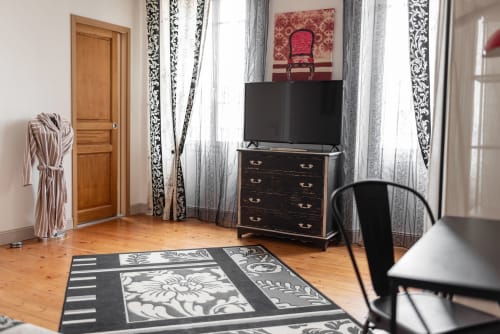 Chambre spacieuse à l'Au Nid De La Madeleine à Gaillac avec parquet, TV écran plat, commode foncée et motifs