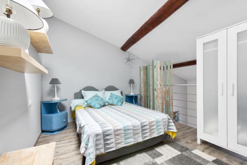 Chambre moderne à Au Nid De La Madeleine à Gaillac : lit queen-size, chevets bleus, poutres en bois, vue sur la ville