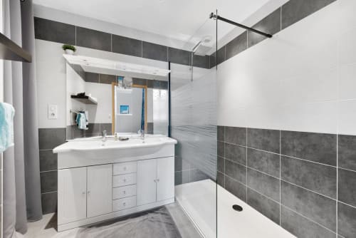 Salle de bain moderne de la chambre Mauzac à Au Nid De La Madeleine, Gaillac avec vasque blanche, carreaux gris et douche vitrée