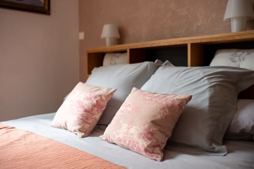 Chambre avec coussins à fleurs roses sur literie blanche à Au Nid De La Madeleine à Gaillac, France