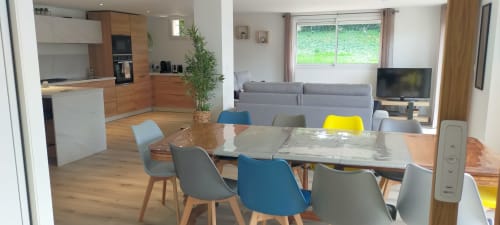 Espace ouvert villa salle à manger et séjour au Gîte des Gônes avec table bois, chaises colorées, cuisine moderne et vue jardin