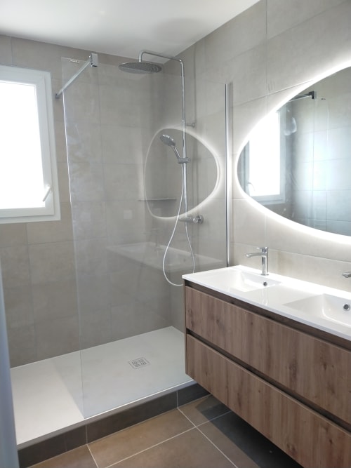 Salle de bain moderne de la villa Gîte des Gônes avec douche à l'italienne, double vasque et miroir rond illuminé