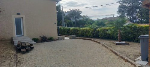 Vue du jardin de la villa Gîte des Gônes à Feyzin avec patio, zone de gravier, haies et palmier