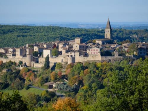 Village médiéval de Gaillac perché sur une colline avec ses bâtiments en pierre, clocher et forêts automnales