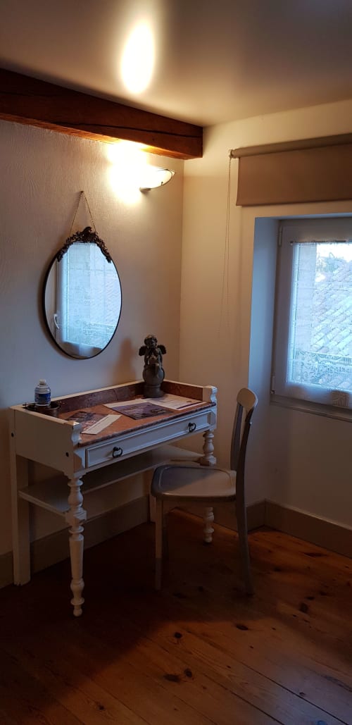 Chambre Muscadelle à Au Nid De La Madeleine à Gaillac avec bureau blanc, miroir rond et vue sur la ville dans ce gîte français