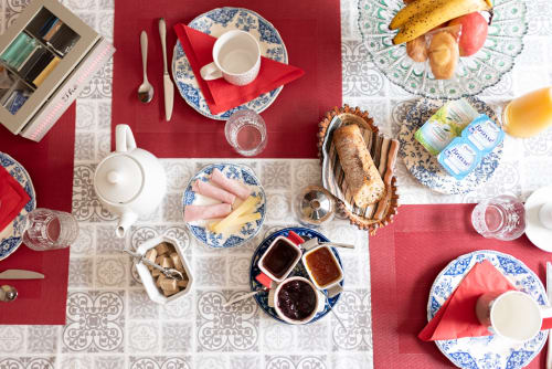 Petit-déjeuner raffiné Au Nid De La Madeleine avec viennoiseries, charcuteries, confitures et service de thé sur fond rouge