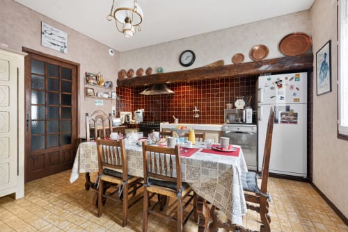 Salle à manger rustique au Gîte Au Nid De La Madeleine à Gaillac, avec table en bois, assiettes en cuivre et carrelage rouge