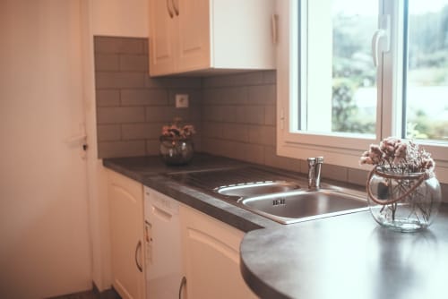 Cuisine moderne du cottage Bobochic à ART DE VOYAGER, Étretat, avec évier inox, plan de travail foncé et vue sur le jardin