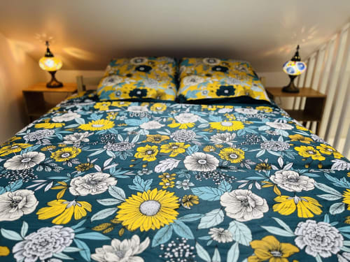 Literie aux motifs floraux en bleu canard et jaune au cottage Art de Voyager à Étretat, France