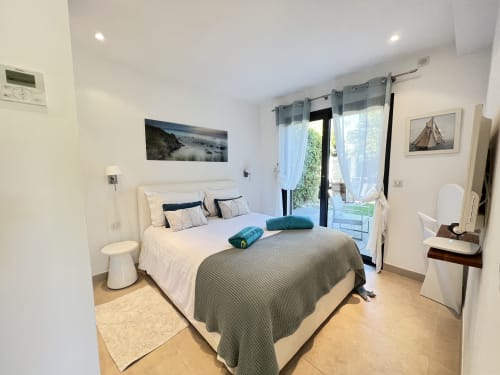 Chambre lumineuse à la Villa La Cabane, Cap d'Antibes, avec lit queen-size, baies vitrées vue piscine et équipements modernes