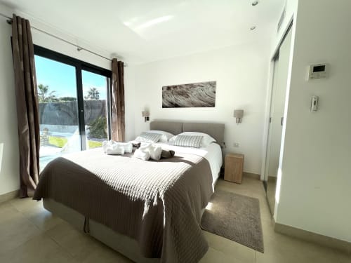 Chambre moderne et lumineuse à la villa de Cap d'Antibes avec vue sur la piscine, lit queen-size, salle de bains attenante et accès à la terrasse